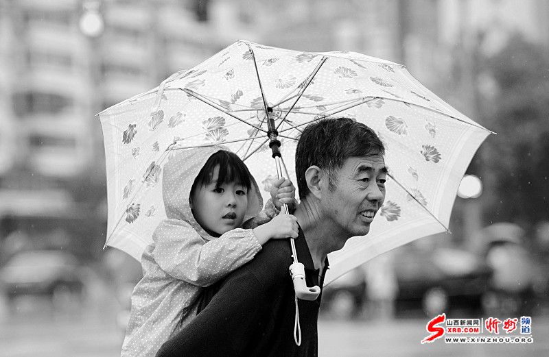 15日，一位太原市民背着孩子在雨中前行。当日，太原市小雨淅沥，最高气温降至24℃以下，令人感觉凉爽舒适。